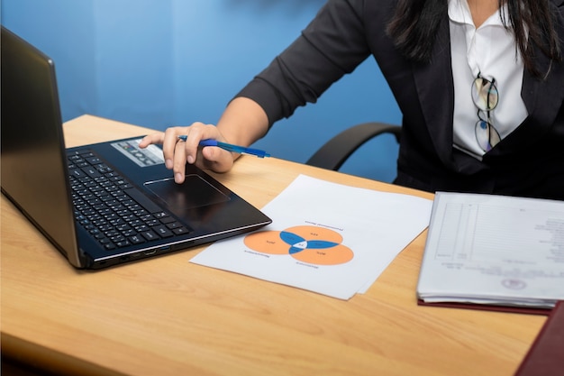 Close Up. Business women use hand and paper writing at graph, Using Computer Notebook laptop.