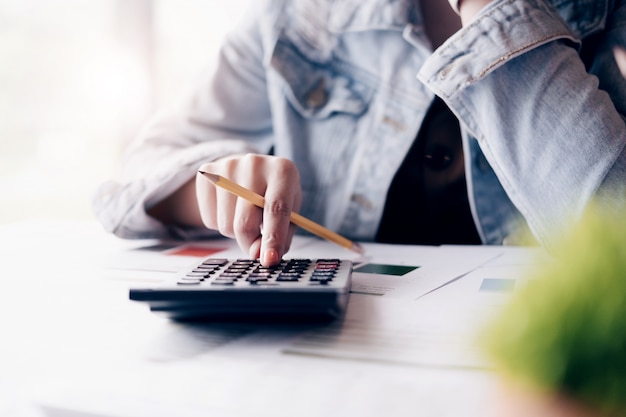 Close up of businessman or accountant hand holding pencil working on calculator 