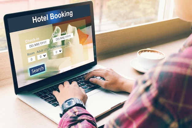 Photo close-up of businessman booking hotel room while using laptop