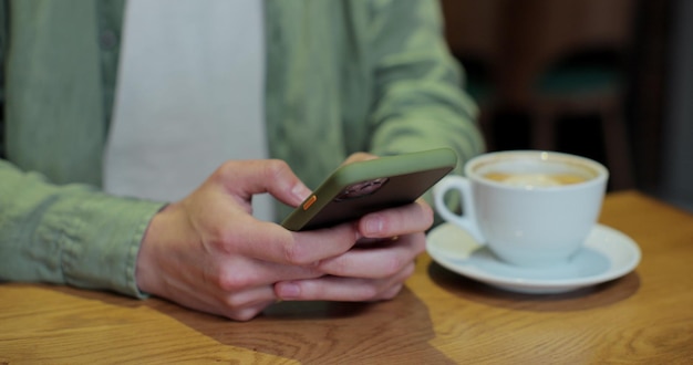 Крупный план бизнесмена в кафе, сидящего за столом и читающего телефонное сообщение или загружающего приложение для своего мобильного телефона