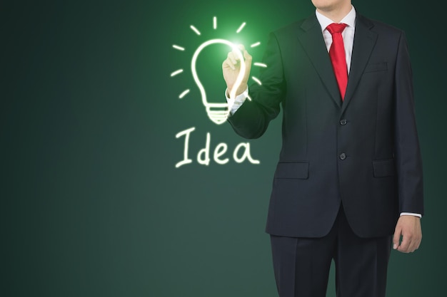 Close up of a businessman drawing a green light bulb sketch