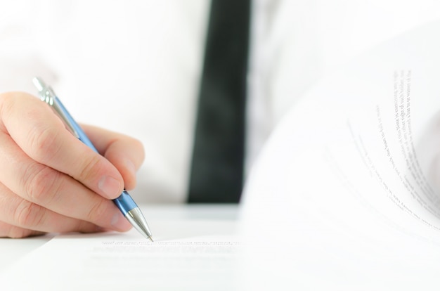 Close up of businessman flipping a page of contract and signing it with a pen