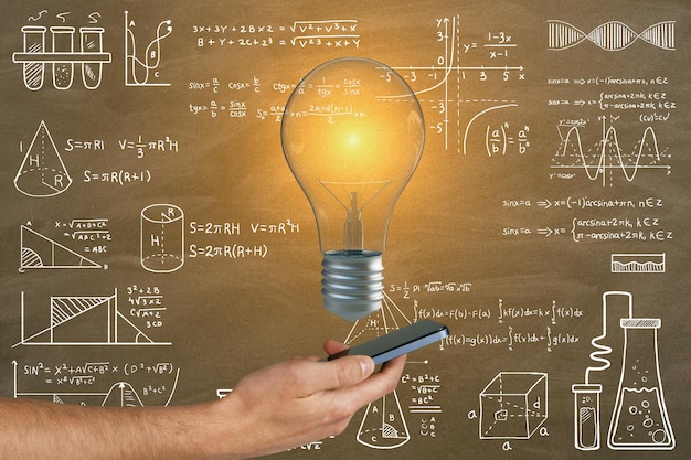 Close up of businessman hand holding smartphone with glowing light bulb on chalkboard wall background with mathematical formulas Science idea and education background