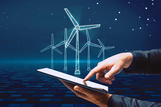 Close up of businessman hand pointing at cellphone with glowing digital wind mill turbine hologram on blue background Wind generator concept