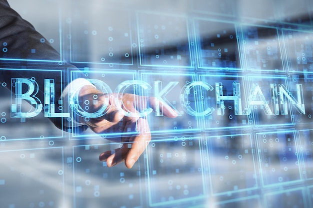 Close up of businessman hand pointing at creative blue cubes blockchain text hologram on blurry office interior background Technology and information concept Double exposure