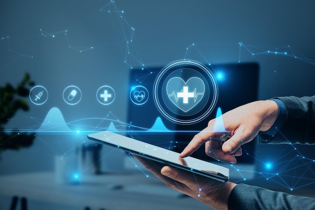 Close up of businessman hand pointing at tablet with creative polygonal medical interface hologram on blurry hospital office interior background. Online healthcare, cardiology and technology concept.