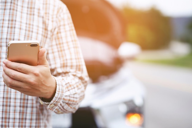 Close up businessman hand using a mobile smart phone call a car mechanic ask for help assistance because car broken roadside people journey friends standing wait beside broken car background