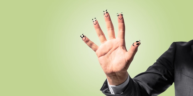 Close up of businessman hand with drawn smileys on yellow background Creativity and emoticon concept