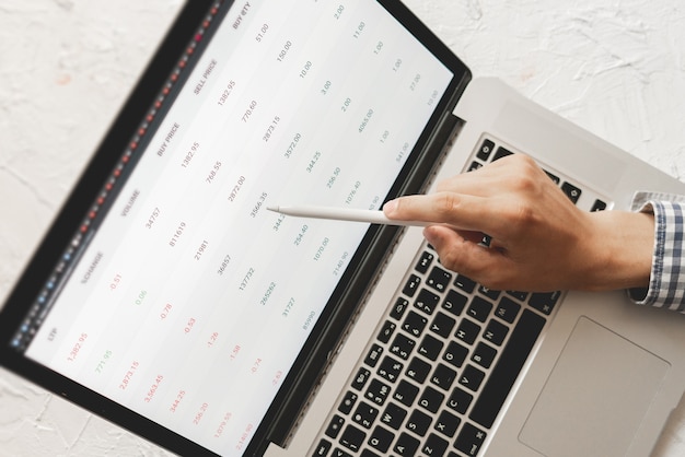 Photo close up businessman hand with pan looking through the details of stock market on laptop