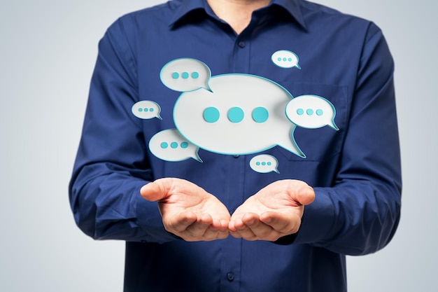 Close up of businessman hands holding creative blue speech bubble on light background Conversation and sms concept