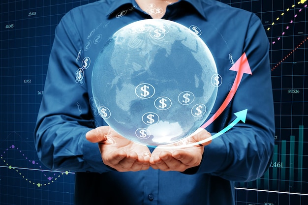 Close up of businessman hands holding glowing globe financial arrows and money signs on blurry background Digital world cryptocurrency online banking trade and technology concept