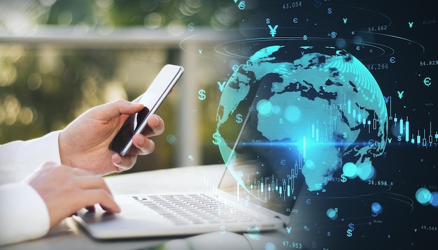 Photo close up of businessman hands using laptop computer and smartphone with glowing money transfer globe on blurry background currency and stock exchange concept double exposure