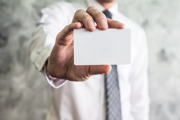 Photo close up of businessman holding white blank card on grunge background