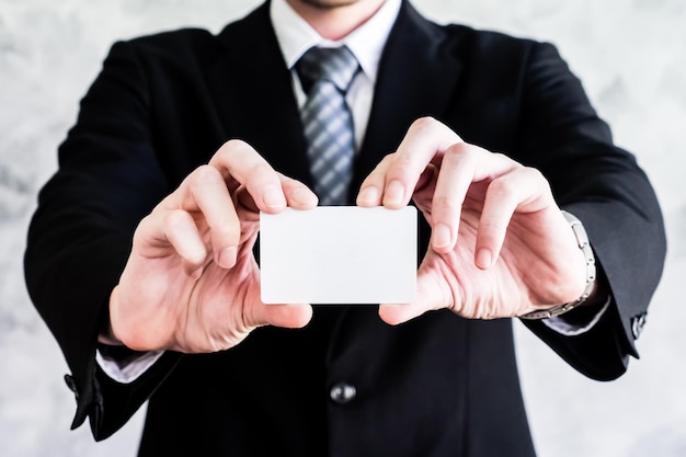 Close up of businessman holding white blank card on grunge background