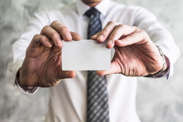 Photo close up of businessman holding white blank card on grunge background