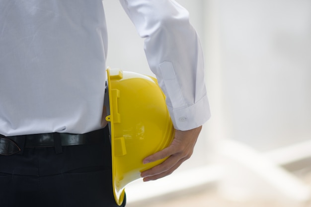 Close up Businessman holding yellow hard hat builder construction estate