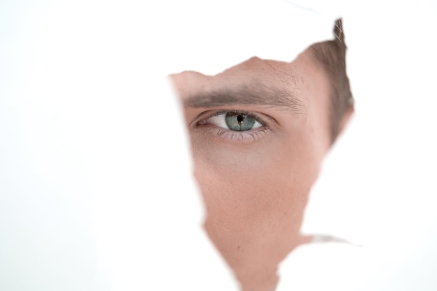 Close up businessman looking through a hole in the paper wall