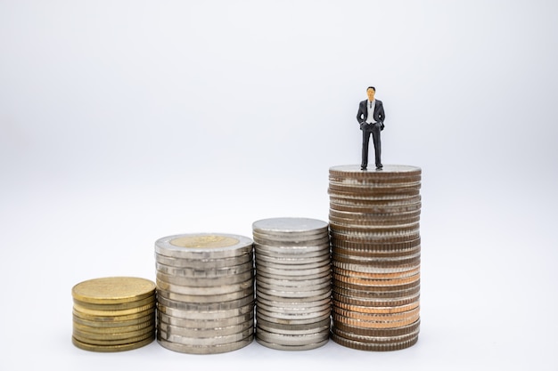 Close up of businessman miniature figures standing stack of coins 