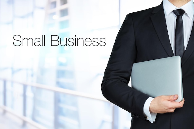 Photo close up of businessman's hands holding laptop and standing near text