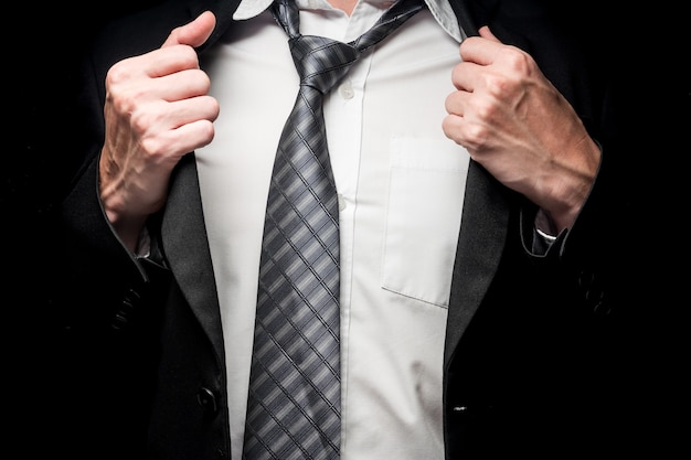 Close up of businessman taking off his suit on black background