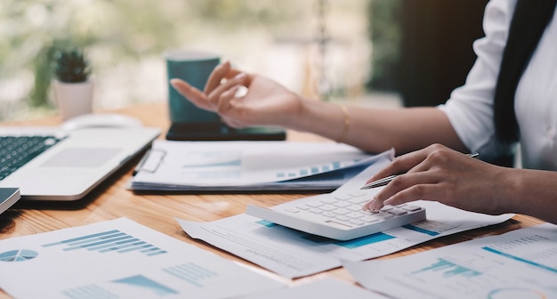 Close up Businessman using calculator and laptop for calaulating finance, tax, accounting, statistics and analytic research concept