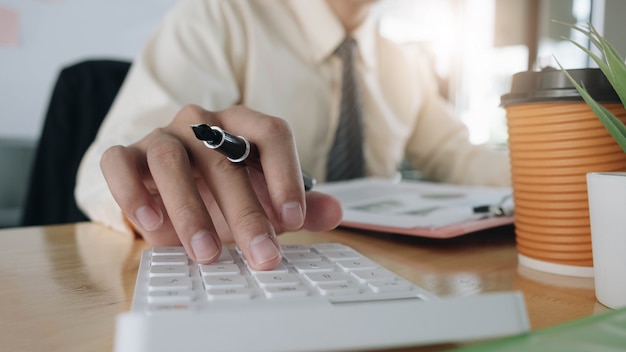 Close up Businessman using calculator and laptop for do math finance on wooden desk in office