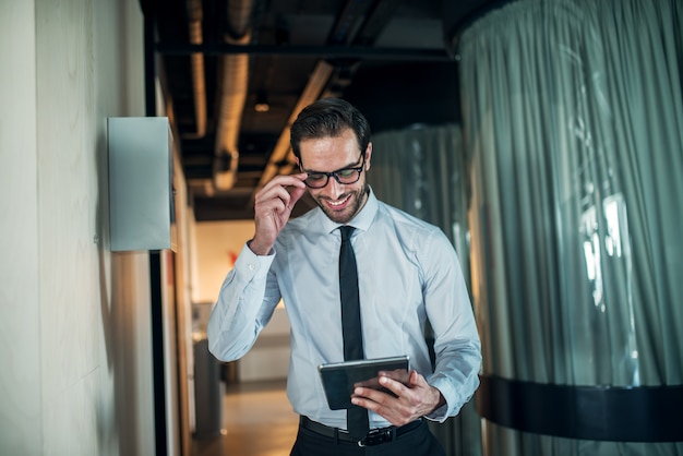 Close up of businessman using tablet while standing in lobby.