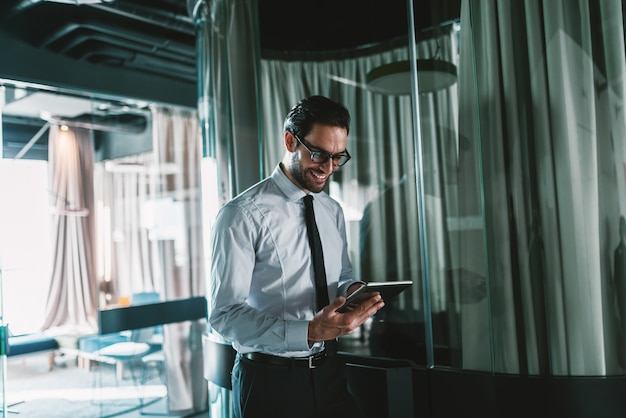 Close up of businessman using tablet while standing in lobby.