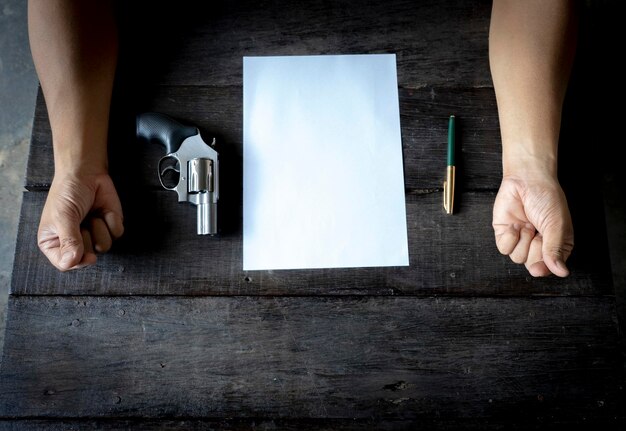 Photo close-up of businessman with gun and paper on table