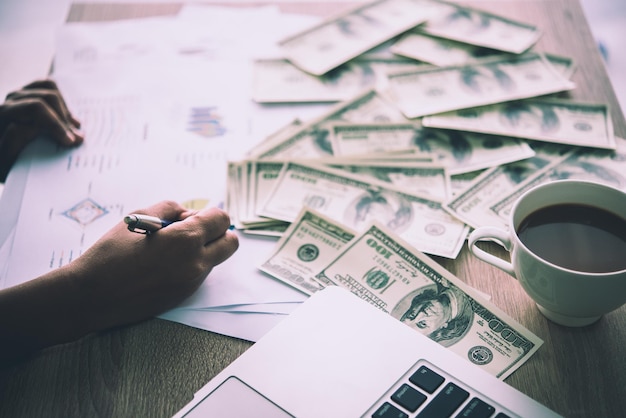 Photo close-up of businessman working over graph with money on table