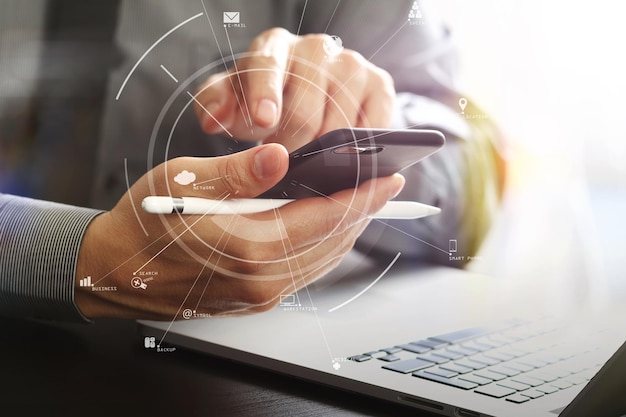 Close up of businessman working with mobile phone and stylus pen and laptop computer