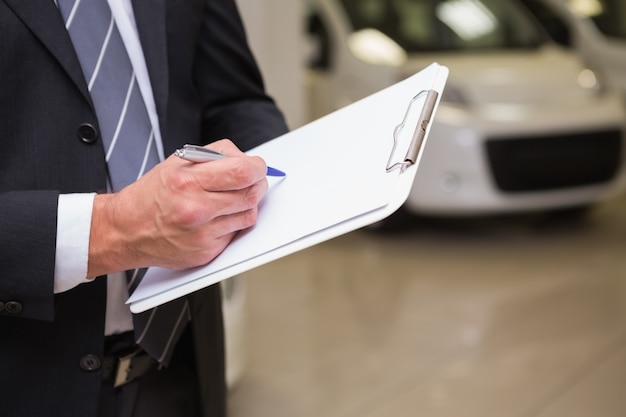 Close up of businessman writing on clipboard