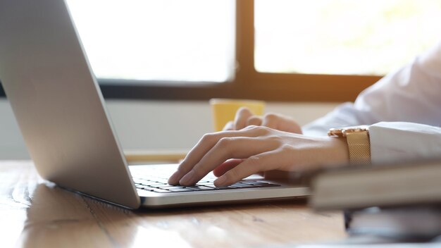 Close up imprenditrice o ragioniere mano che tiene la penna lavorando sul computer portatile per calcolare i dati aziendali