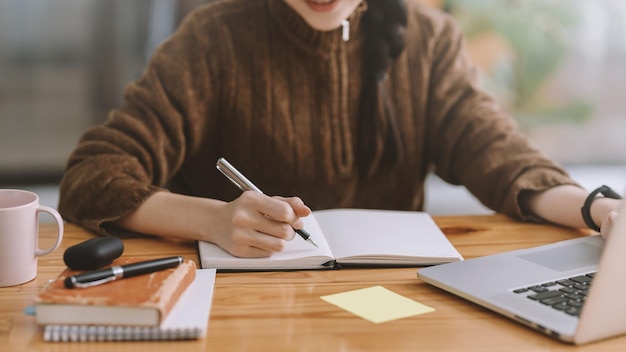 Close up Businesswoman hand using pen taking notes in office