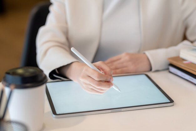 Close-up of a businesswoman hand working on a digital tablet blank screen at the office.