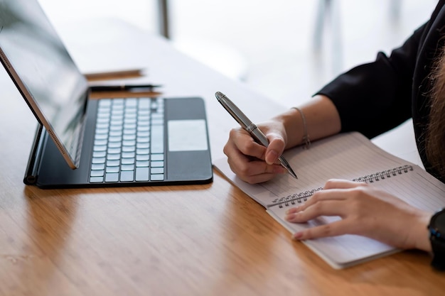 close up of businesswoman holding a pen take notes using a tablet at the office