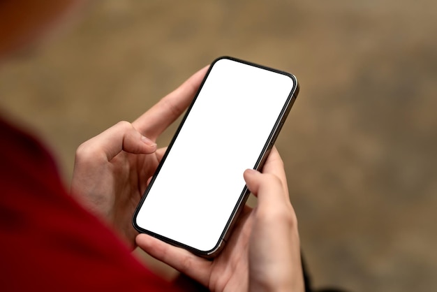 Close-up of businesswoman holding a smartphone blank white screen and relax at the office. Mock up.