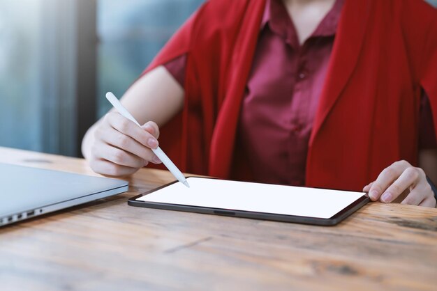 Close-up of businesswoman holding a stylus pen with a tablet blank white screen working at the office.