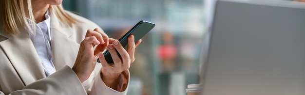 Close up of businesswoman use phone during working on laptop in cafe distance work concept