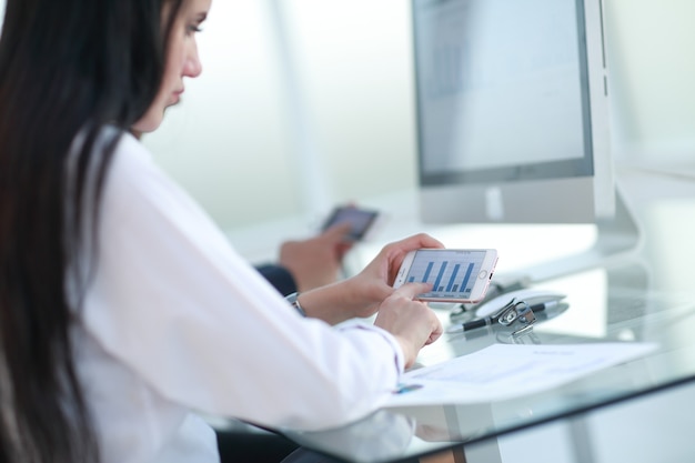 Close up.the businesswoman uses her smartphone to work with financial data.people and technology