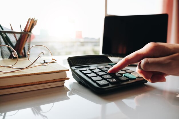 Фото Бизнесменка с калькулятором и ноутбуком для математических финансов на деревянном столе в офисе