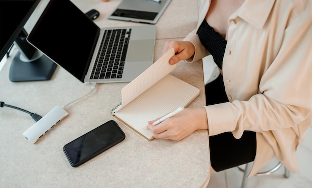 Close up of businesswoman working at home office on laptop and making notes Young happy female student studying in online university