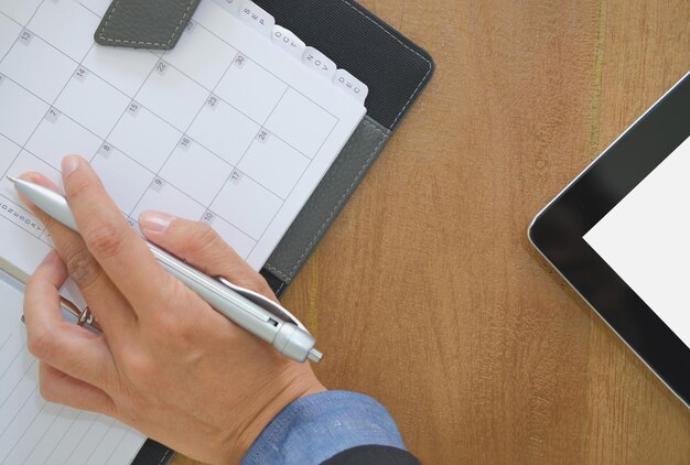 Photo close-up of businesswoman writing in book on table