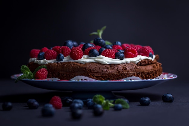Photo close-up of cake with berry fruits on table against black background