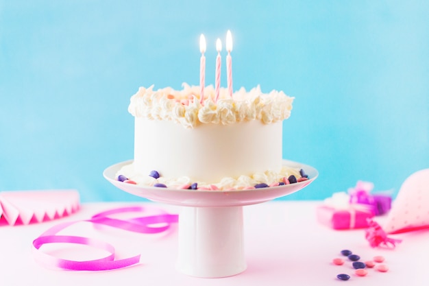 Close-up of cake with burning candles on pink backdrop