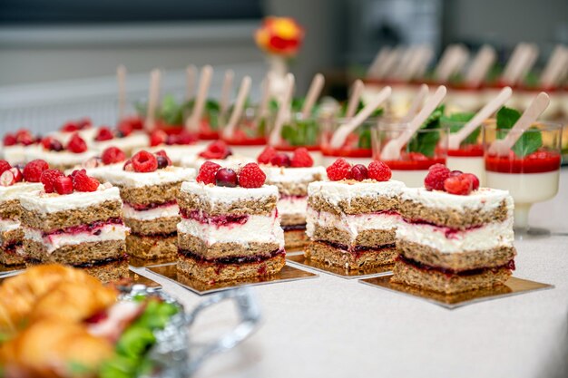 Photo close up of cakes with fresh fruits and berries arranged in a row on a party table