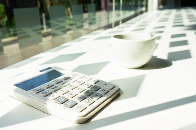 Photo close-up of calculator and cup on table