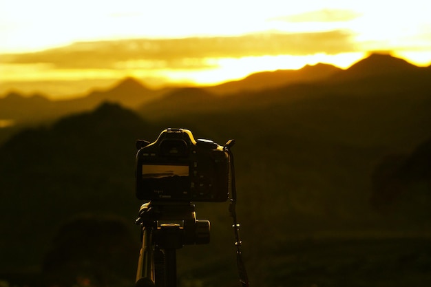 Photo close-up of camera against mountain during sunset