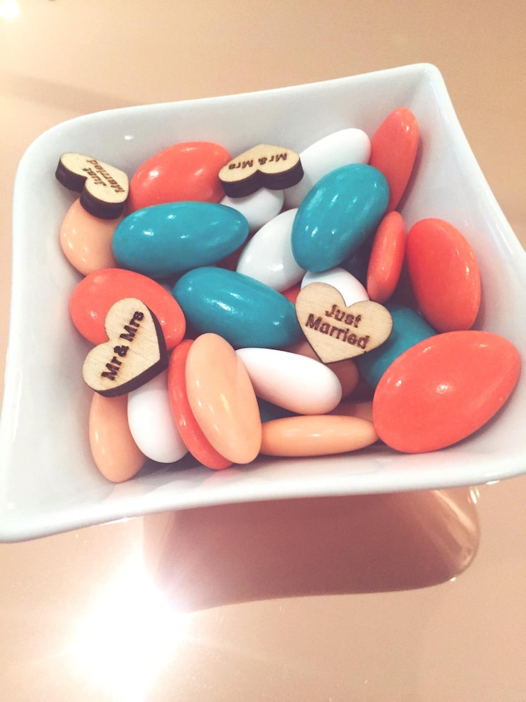 Photo close-up of candies with signs on hear shapes in bowl on table