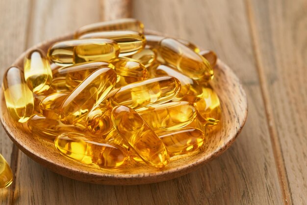 Close up capsules with Vitamin D E or Omega 369 fatty acids in bottle on old wooden backgrounds Food supplement oil filled fish oil Natural supplements for healthy good life concept Banner